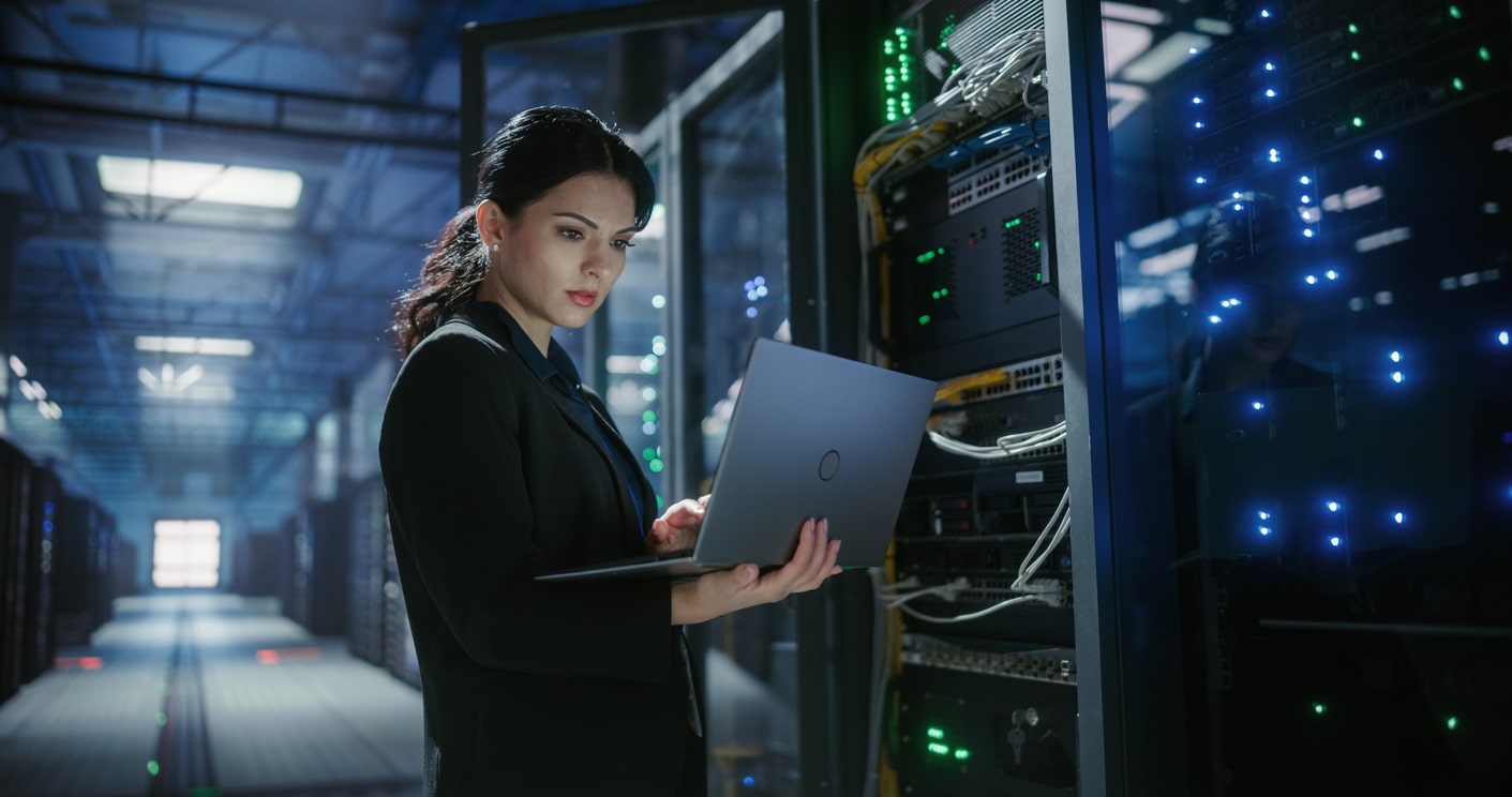 IT engineer uses a laptop to check and monitor server equipment. Software diagnostics, internet connectivity, and technical service support for stable infrastructure and system performance.